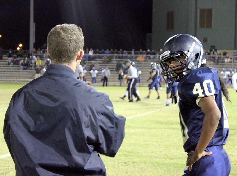 Sophomore outside linebacker Xavier Mendez gets coached up on the sideline by junior varsity defensive coordinator Christopher Randolph. Akins lost to Anderson.