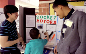 Senior Josue Gonzalez and his partner show young students their Rocket Motors science fair project. This was the first science fair in Akins history.