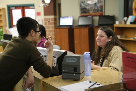 Librarian Bonnie Hauser is talking and checking out a student, one of her may tasks throughout the day. 
