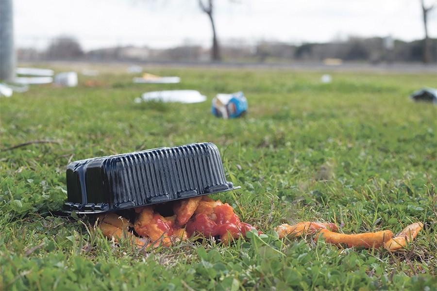 A bowl of spicy chicken nuggets is spilled on the ground near the basketball slab
along with other articles of trash laying in the distance.