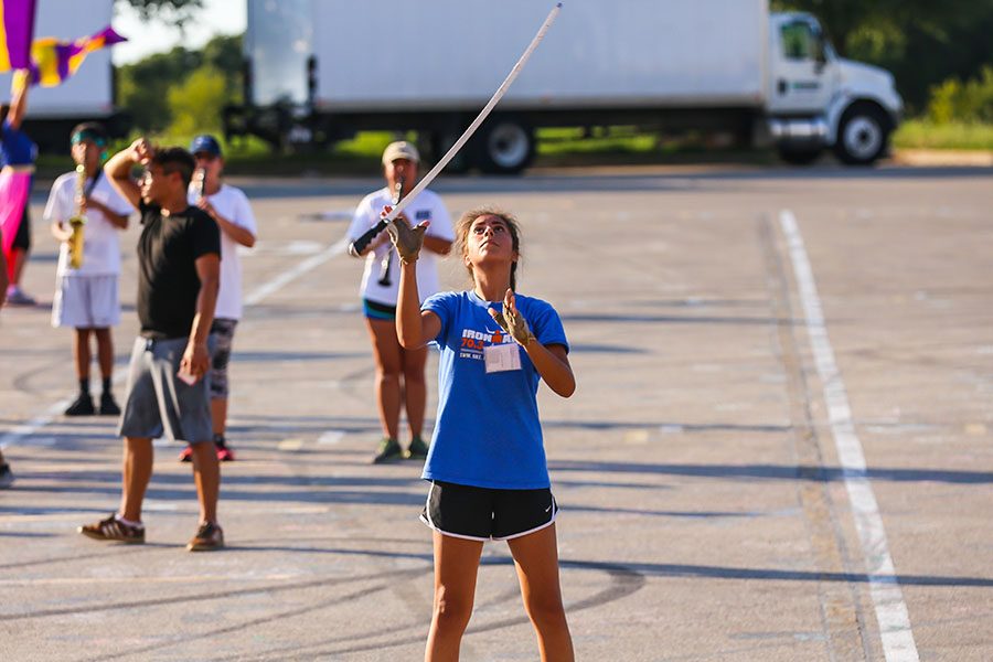 Senior Raynne Miller-Moya is preforming a saber toss routine with the other color guard members in sync, making sure all of them start and end together when the saber comes back down.