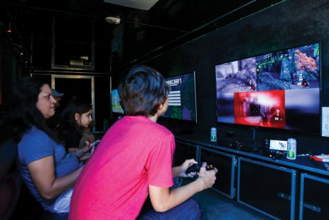 A mother and her two children enjoy  playing COD Black OPS 2 Zombies in the Rolling Video Games truck. The truck carries 4 TV screens and holds up to 16 players