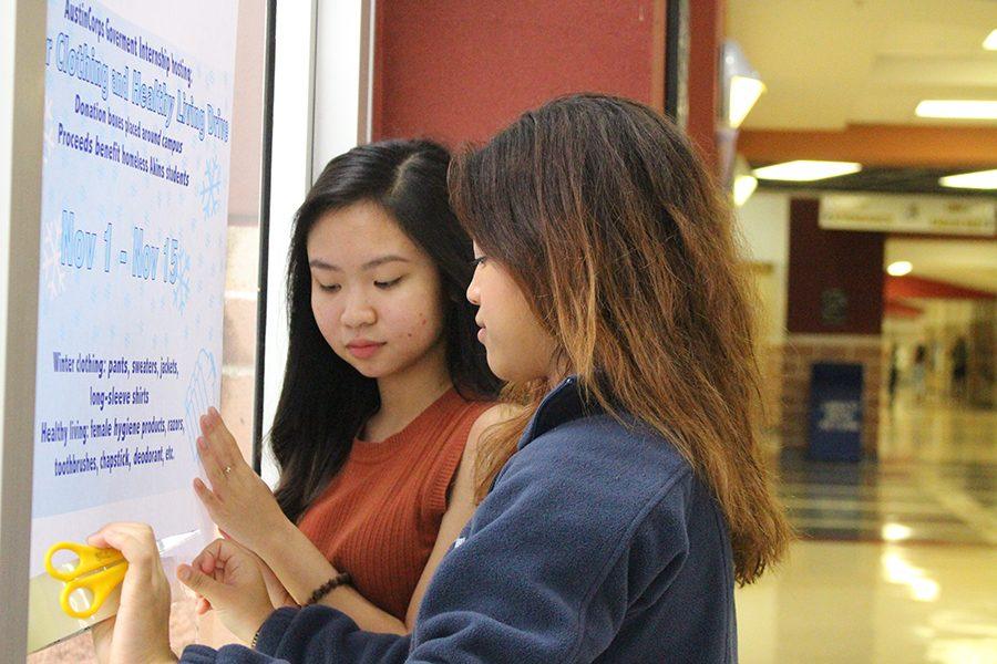 Seniors Tammy Nguyen and Yocelyn Erazo hang up posters for the Winter Clothing and Healthy Living Drive. Boxes were placed around campus with the hope of having students donate items that would help both homeless students and financially unstable students.