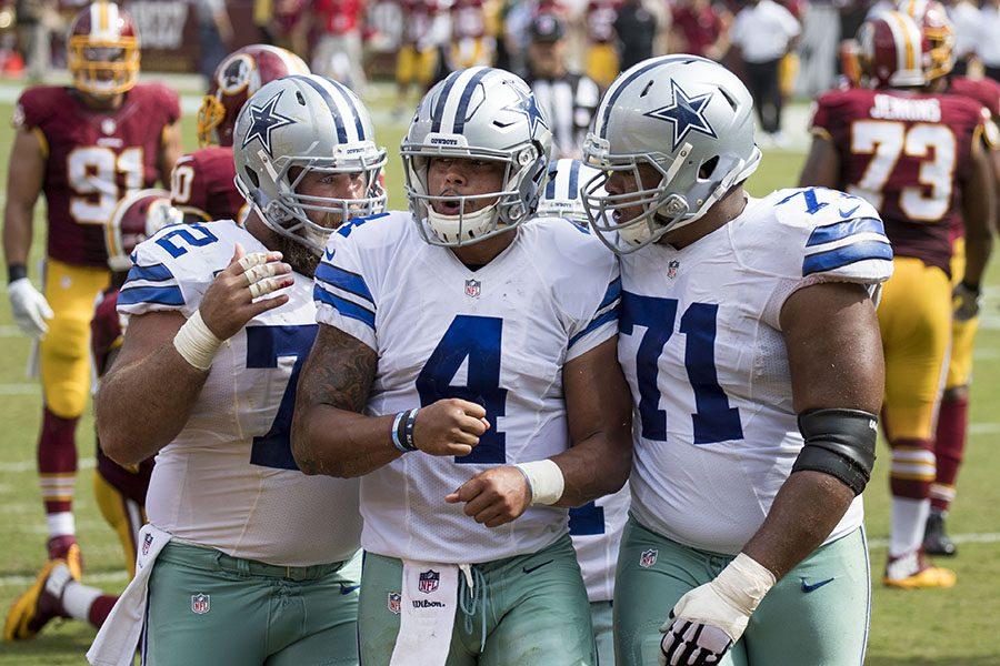 Quarterback Dak Prescott of the Dallas Cowboys is congratulated by teammates after scoring a touchdown in a game against the Washington Redskins at FedExField on September 18, 2016 in Landover, Maryland.