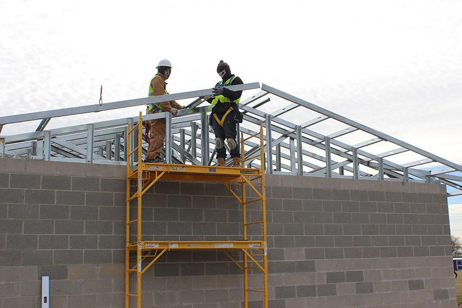 Construction workers work on building the roof on the new bathrooms and storage building on the practice field in February.