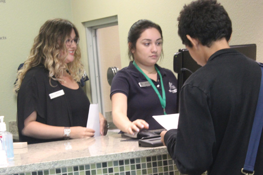 Branch manager Marla Carter and senior Mitzy Martinez work at the bank desk. Interns work after sixth period.