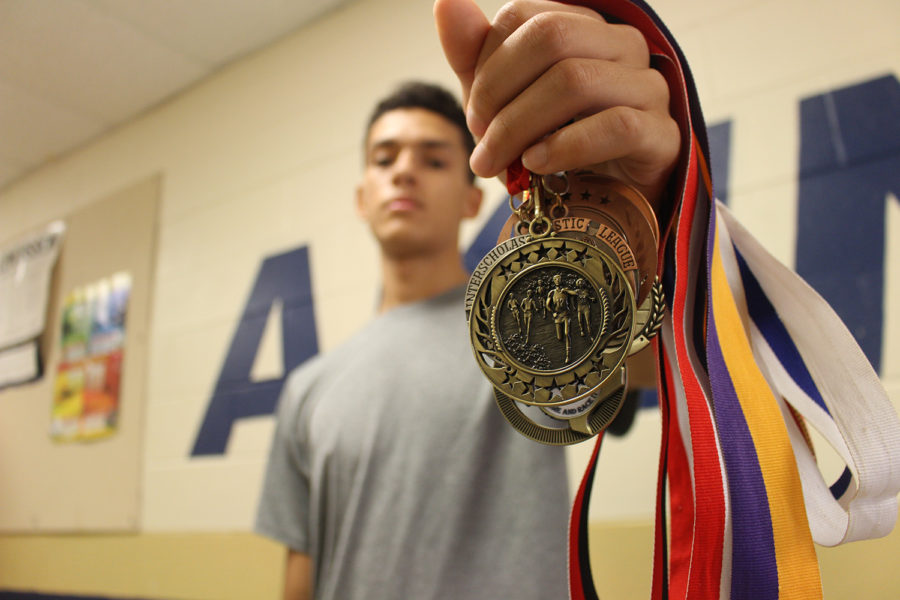 Senior Cassius Serff-Roberts shows off one of his many medals that he has won as a Cross Country runner. He beat an Akins record by running a 5K in less than 15-minutes. Later that month beating his own record with 10 seconds less than the first time.