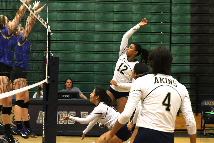 Freshman Shanti Ramdeen (12) goes for a spike as two players form the Anderson Trojans try to black it on Sept. 26. The Lady Eagles lost the game 0-3.
