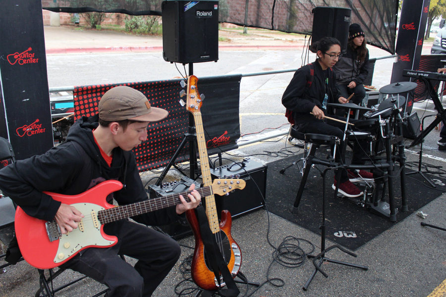 Junior Chance Burrow plays guitar while sophomore Eli Gutierrez plays drums at a Guitar Center activity booth.