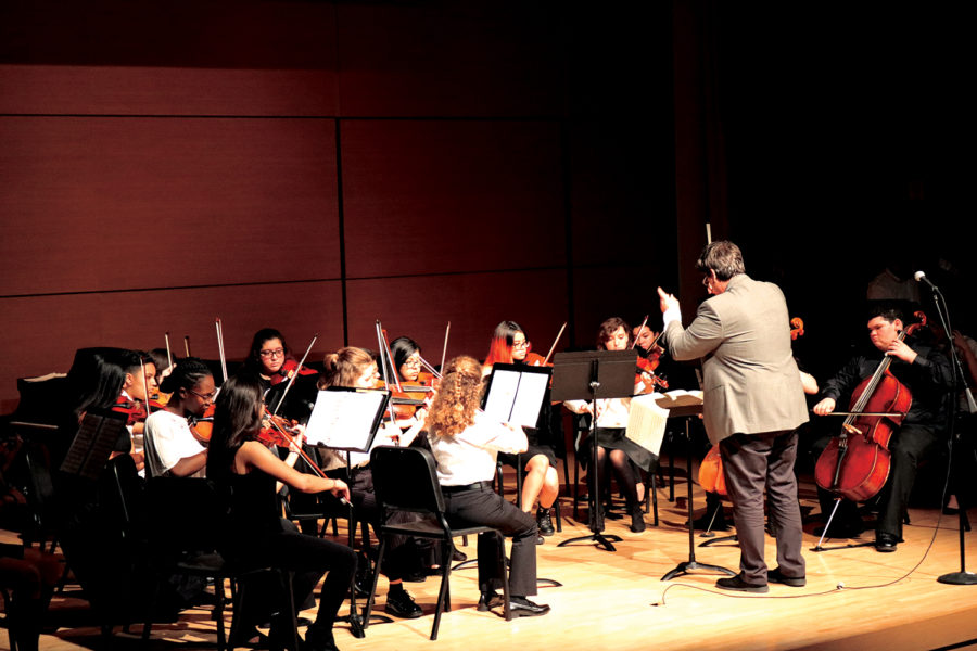 Mann (right) conducts the advanced orchestra during their performance at Texas State University. Mann said that while the preparation for the show was hectic, the performance was significant. “Akins gets to play in it and that’s super,” Mann said.