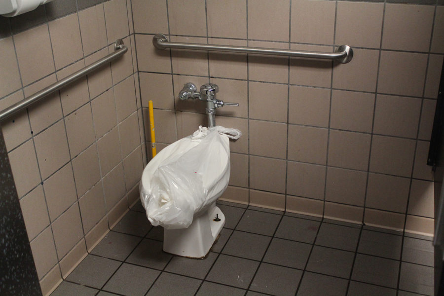 A toilet is bagged off in an upstairs bathroom, needing repairs.