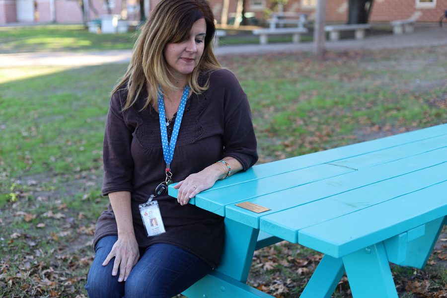 SCORES teacher Kari Janner sits at one of the two new picnic tables that were donated to the campus to honor an alum who recently passed away.