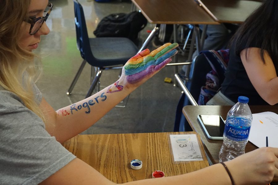 Teacher+Merin+Rogers+shows+students+how+they+can+paint+their+hands+for+a+lesson+in+her+American+Sign+Language+class.+Students+have+to+adjust+to+sign+language+being+a+visual+language.