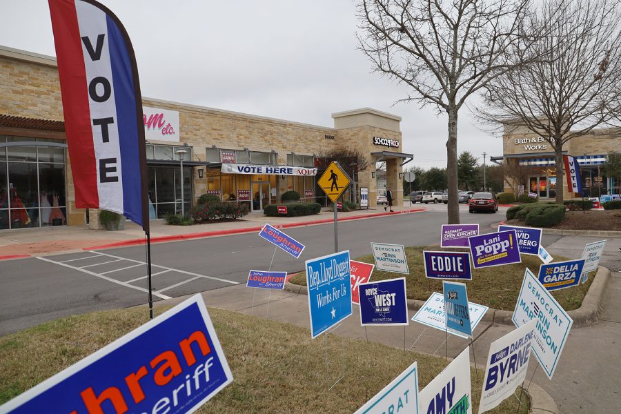 Campaign signs are squeezed into a parking lot island in front of the voting location in Southpark Meadows shopping center. It is the closest early voting location near Akins High School.