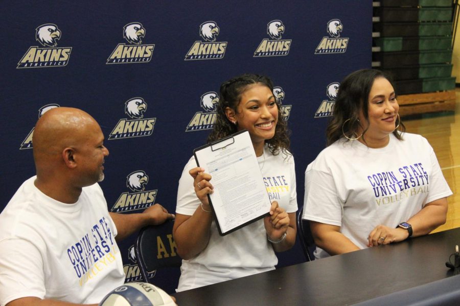 Making history- Senior Shanti Ramdeen (middle bottom), signs her letter of intent to play college volleyball at Coppin State University in Maryland. Ramdeen will be the very first volleyball athlete from Akins to attend a NCAA Division I school on an athletic scholarship. Her family, friends and  teammates celebrated  her accomplishment with her in a ceremony held in the Akins gym on Nov. 11. Two of her middle school volleyball coaches also attended the event.
