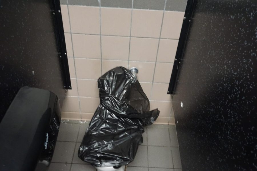 A toilet is bagged up to prevent use after being damaged in an upstairs boys restroom.