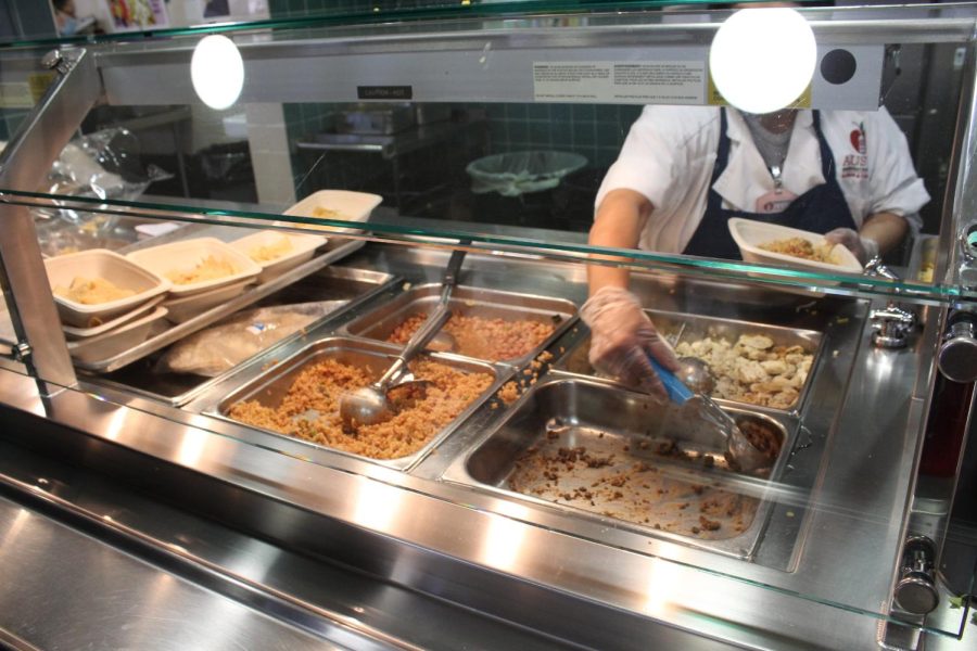 A cafeteria staff member serves the remaining ground beef to a student during A lunch. The district offers 15 different entrees at high schools, giving students a variety of options to choose from. Rice, chicken, and beans are also being served.