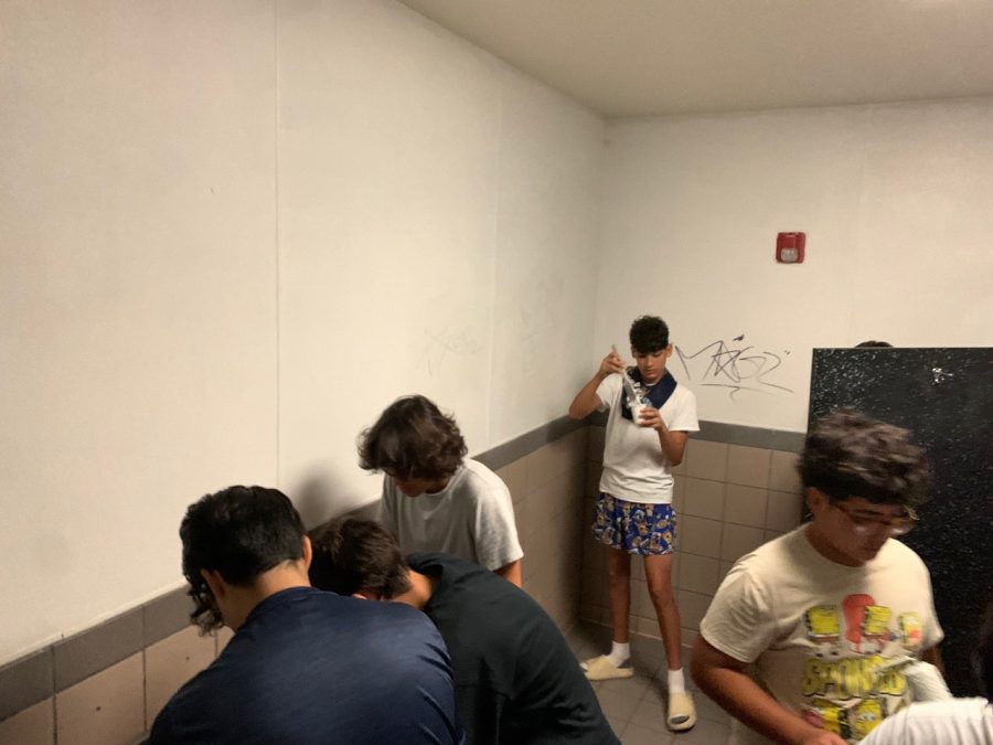 Football players paint walls with white paint to cover graffiti in bathrooms at Akins during a Saturday volunteer project.
