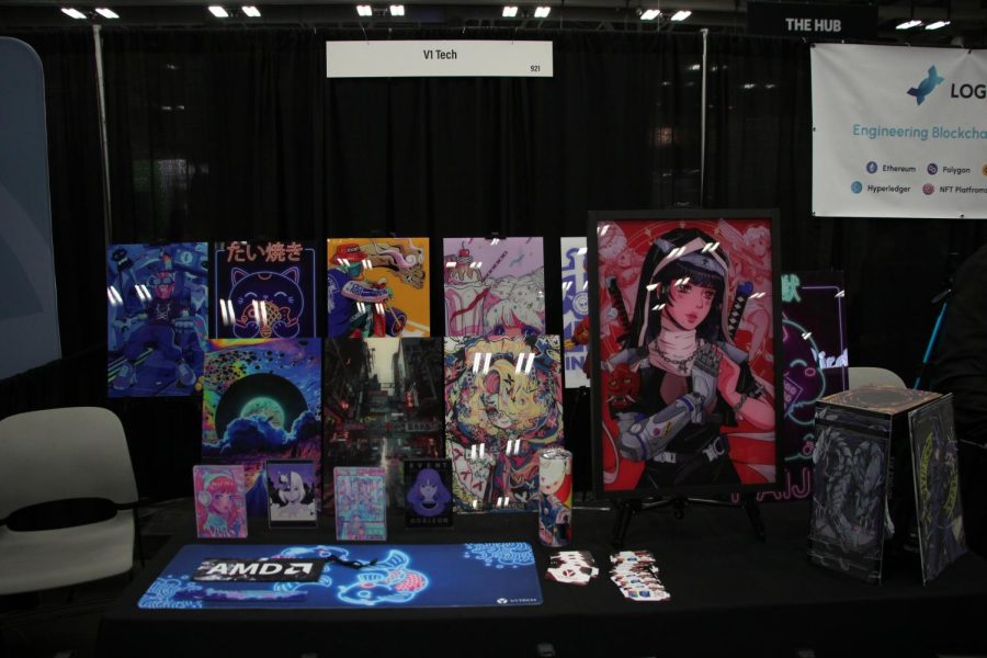 A booth hosted by V1 Tech at the creative industries expo showcasing art for sale made by various independent artists. V1 Tech holds art and accessories made by independent graphic artists for sale, sharing a commission along the way.