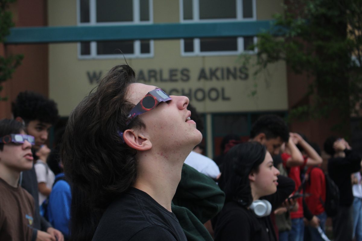 A student views the solar eclipse while standing in front of the main entrance to Akins during the solar eclipse on April 8.