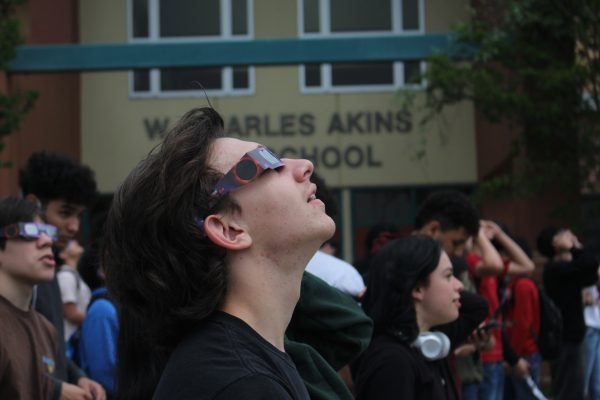 A student views the solar eclipse while standing in front of the main entrance to Akins during the solar eclipse on April 8.