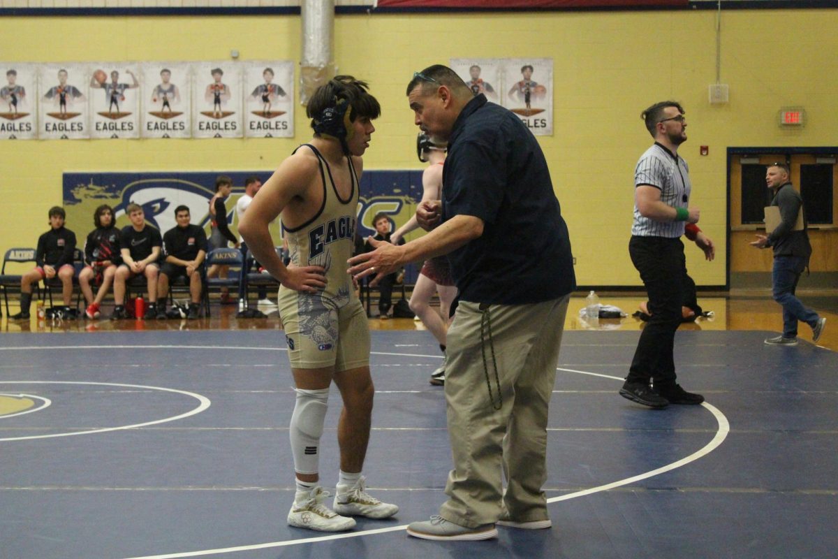Coach Roy Tambunga talks with wrestler Jacob Ortiz at Akins High School against Bowie High School on Jan. 10. Ortiz won this match right after speaking with him.