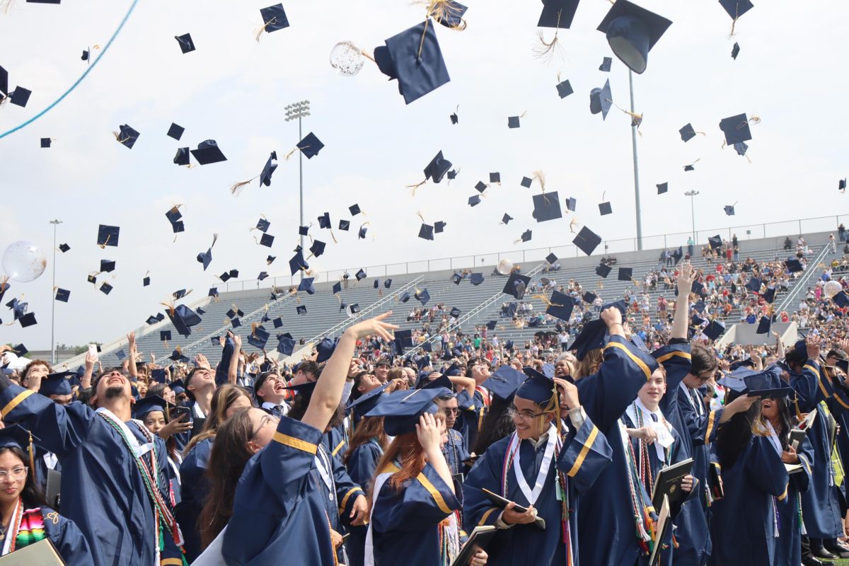 Members of Akins Class of 2024 toss their hats in the air after walking the graduation stage at Burger Stadium on May 28.