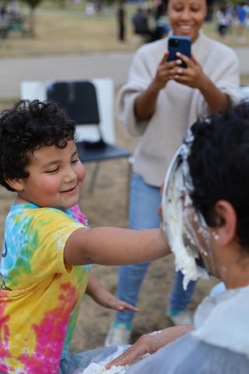 An attendee of Blue and Gold Night pieing Christopher Aguilar at the NHS pie a teacher booth.