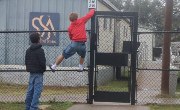 A student attempts to climb over the new fence near that encloses the area around the portables classrooms. A new law requires the
school to lock the gates after fences were installed this summer.