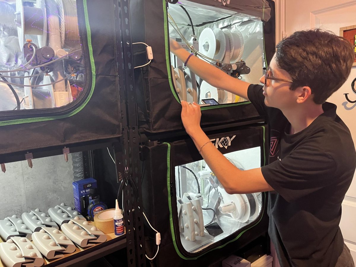 Student entrepreneur Jaxzen Perez fixes a 3D printer which he stated would jam frequently.